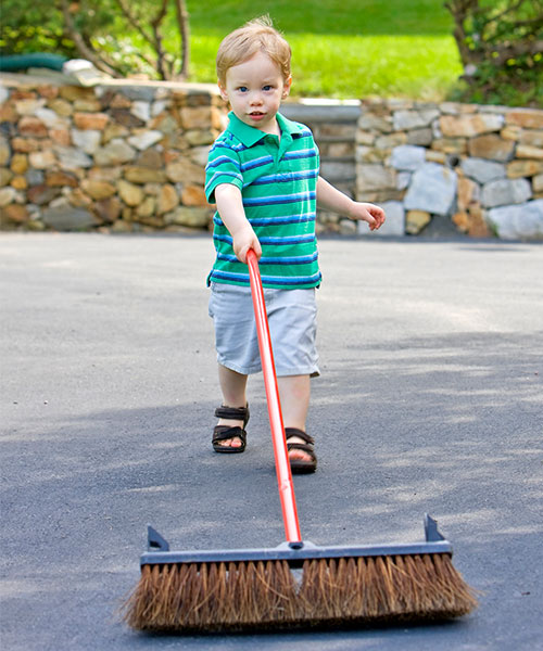 Young child with broom sweeping the street, to help prevent stormwater pollution.