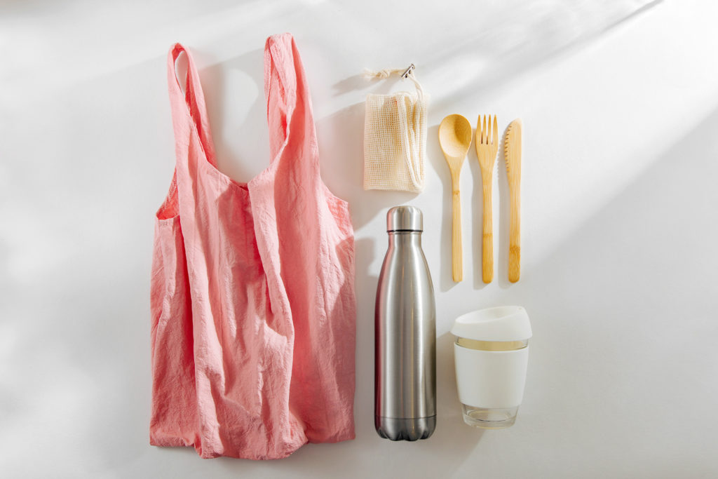 Set of Eco friendly bamboo cutlery, pink eco bag reusable coffee mug and water bottle. Sustainable lifestyle. Plastic free concept.