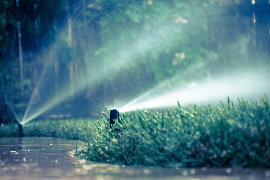 A photo of water sprinklers watering grass during a rainstorm